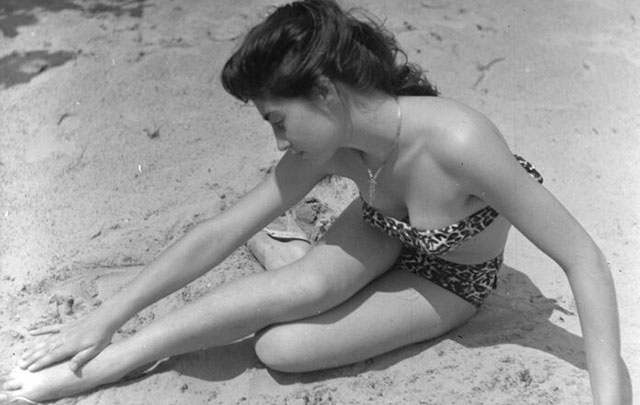 Amedeo Montemaggi Rimini foto in bianco e nero di ragazza in costume stesa sulla sabbia che si tocca una caviglia