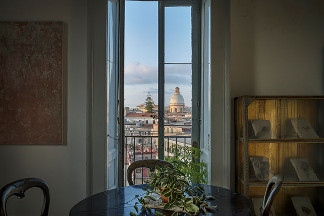 Anton Giulio Onofri Roma foto a colori di stanza con al centro un tavolo con delle piante davanti a finestra aperta con veduta su Roma