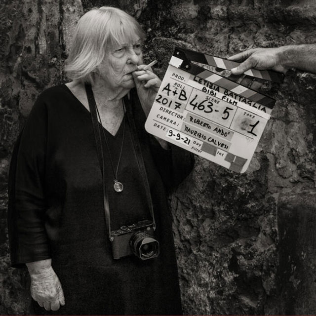 Lia Pasqualino Palermo foto in bianco e nero della fotografa letizia Battaglia che fuma una sigaretta sul set del film mentre una mano tiene il ciak davanti al suo viso