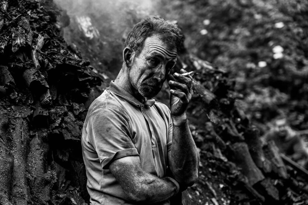 Mirko Torresani Milano foto in bianco e nero di uomo sporco di fuligine fuma una sigaretta