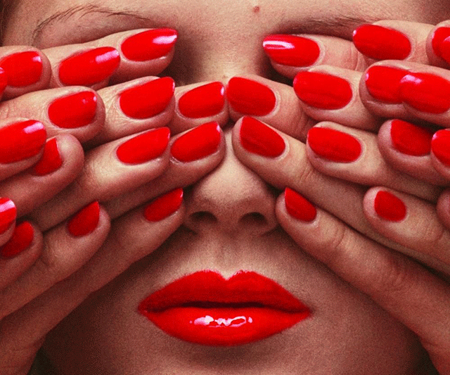 Guy Bourdin Milano foto a colori di viso di donna con rossetto rosso lucido e gli occhi coperti da tante mani con smalto rosso