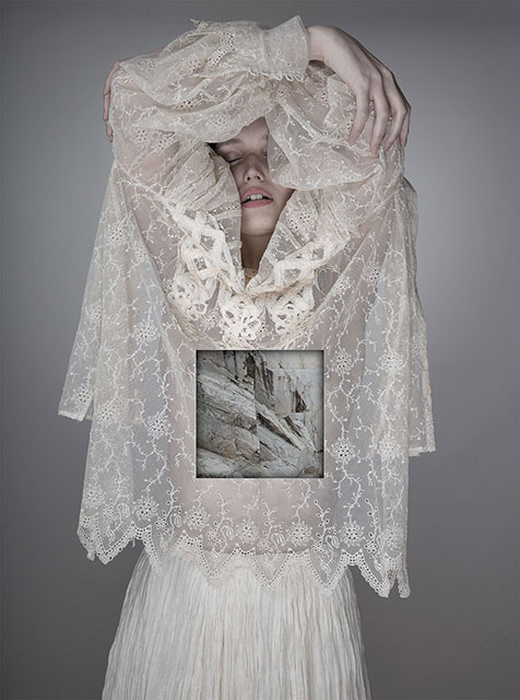 Matteo Basilè Milano foto a colori di ragazza con camicia di pizzo bianca e le braccia sulla testa e occhi chiusi con foto di rocce bianche sull'addome