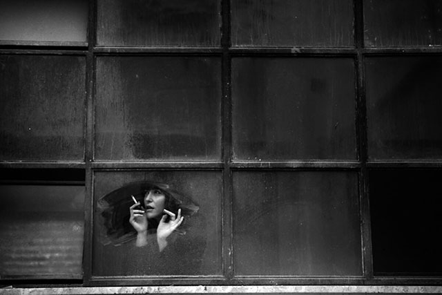 Daniele Notaro Lecce foto in bianco e nero di donna dietro una grande finestra che fuma una sigaretta