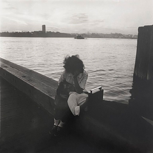 Fem Frames Milano foto in bianco e nero di donna seduta su un muretto vicino al mare con uomo sdraiato con la testa sulle sue gambe