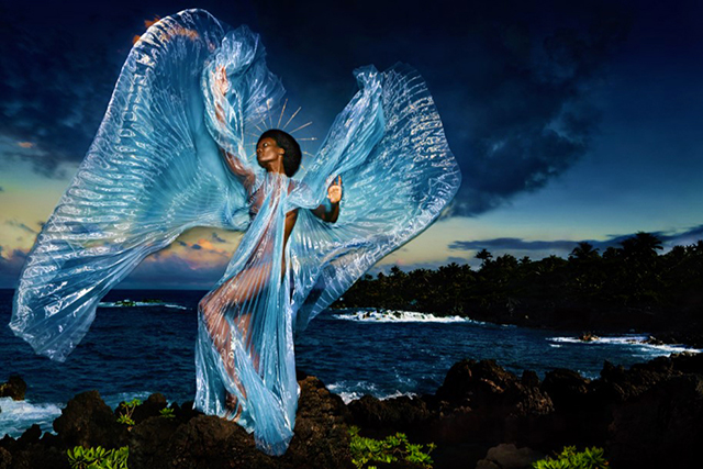 David LaChapelle Trieste foto a colori di donna di spalle al mare sugli scogli con vestito trasparente azzurro