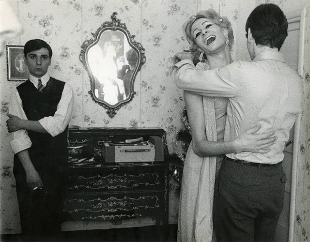 Lisetta Carmi Roma foto in bianco e nero di tre uomini in una stanza due che ballano e uno appoggiato ad un mobile che guarda