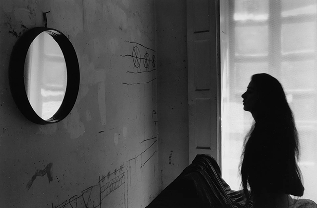 Enzo Obisio Torino foto in bianco e nero di donna nella penombra di una stanza che guarda uno specchio tondo attaccato al muro