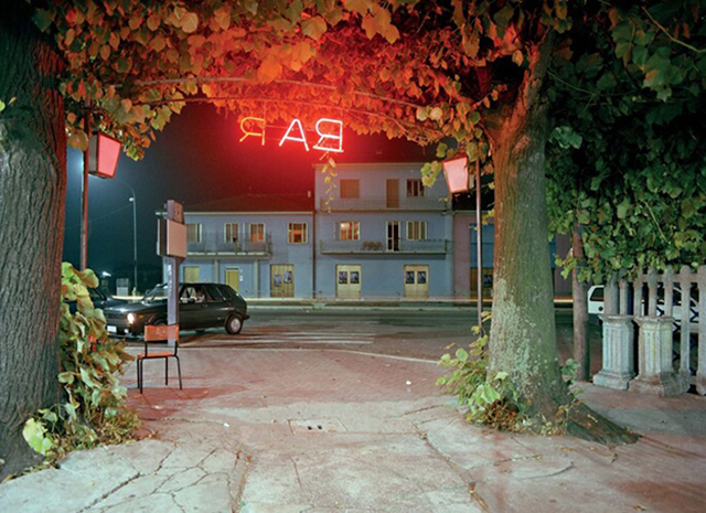 Luigi Ghirri Guastalla foto a colori di vialetto di sera illuminato da insegna rossa al contrario con scritto Bar