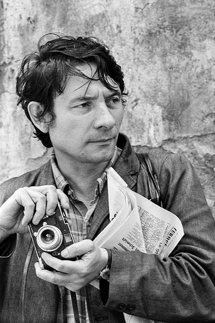 Mario Dondero Milano ritratto in bianco e nero del fotografo Mario Dondero con giornale e macchina fotografica in mano