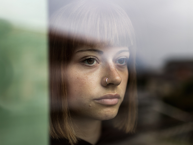 Matteo Trevisan Roma primo piano a colori di ragazza che guarda fuori da una finestra con viso triste