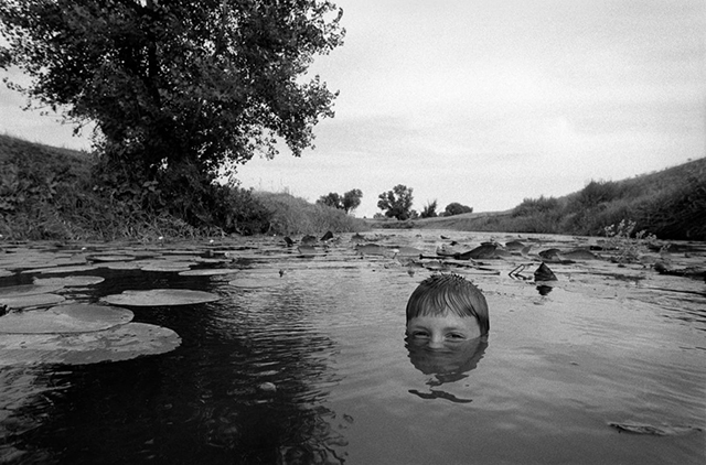 Anteprima Asincronie Alghero foto in bianco e nero di bambino immerso fino al naso nell'acqua di un lago