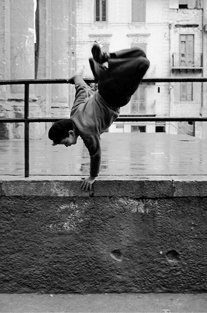 Ferdinando Scianna Catania bambino che fa capriola appoggiato ad una ringhiera