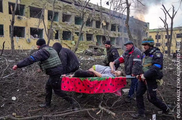 World Press Photo 2023 Torino foto a colori di uomini che portano sulla barella una donna incinta ferita in mezzo alle macerie