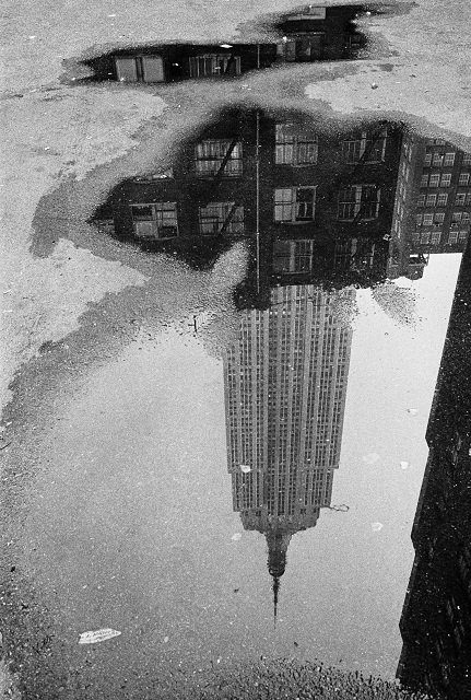André Kertész Torino foto in bianco e nero di grattacielo riflesso in una pozzanghera