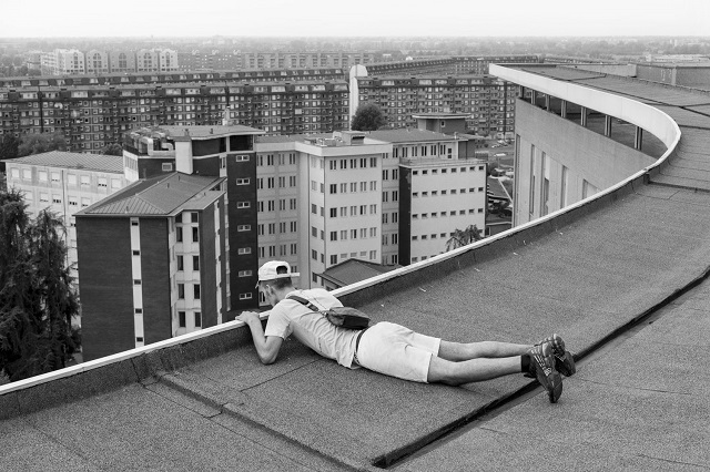 Angelo Leonardo Roma foto in bianco e nero di uomo sdraiato sul bordo del tetto di un palazzo