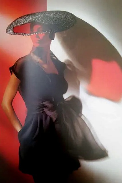 Gian Paolo Barbieri Bard foto a colori di modella con cappello in posa con sfondo rosso e bianco