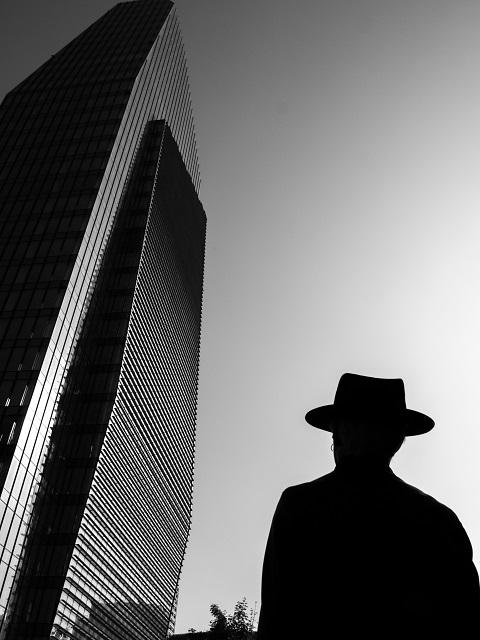 Giorgio Galimberti Milano foto in bianco e nero di uomo con cappello in controluce che guarda grattacielo