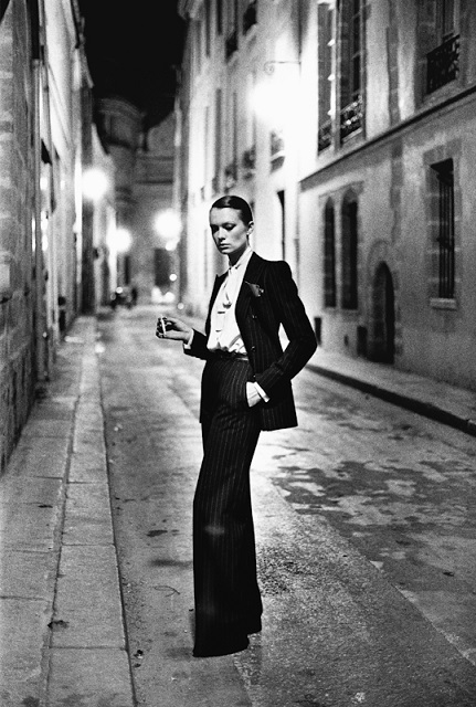 Helmut Newton Roma foto in bianco e nero di modella con abiti maschili e sigaretta in mano in posa in un vicolo