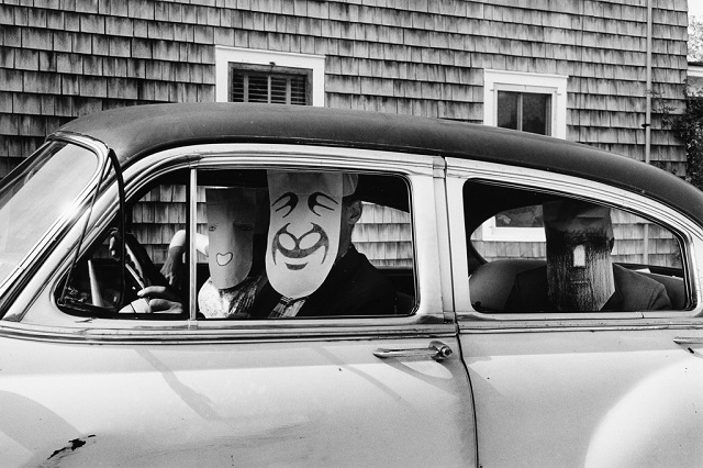 Inge Morath Caraglio foto in bianco e nero di persone con maschere sul viso dentro una macchina