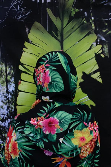 off - oculus foto festival venezia foto a coloi di persona di spalle con tuta attillata intera floreale appoggiata a grossa foglia verde