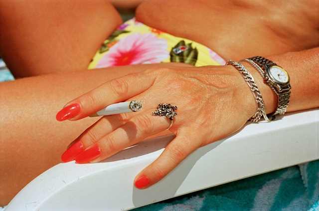 Martin Parr Milano foto di mano di donna sdraiata sul lettino da mare con unghie rosse e sigaretta