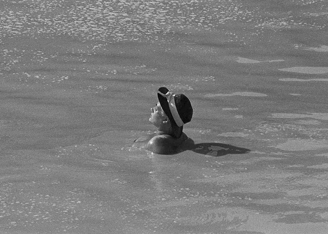 Melo Minnella Castelbuono foto in bianco e nero di donna che prende il sole in mare con cappello