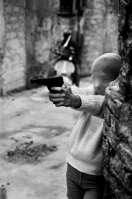 Letizia Battaglia Aosta foto in bianco e nero di bambino con calza in testa che punta una pistola